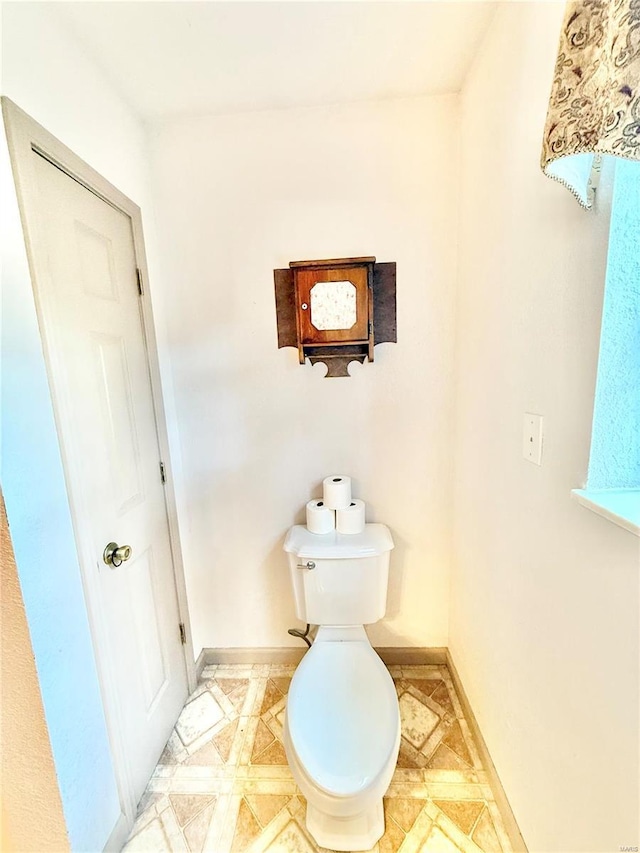 bathroom featuring baseboards and toilet
