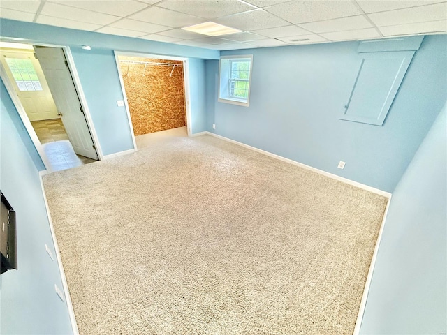 basement with baseboards, carpet, and a drop ceiling