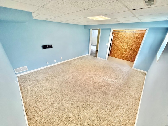 finished below grade area with baseboards, visible vents, a drop ceiling, and carpet