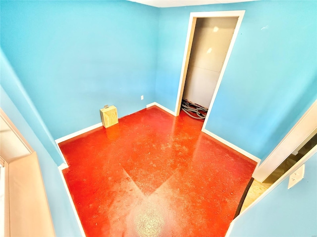 spare room featuring concrete flooring and baseboards