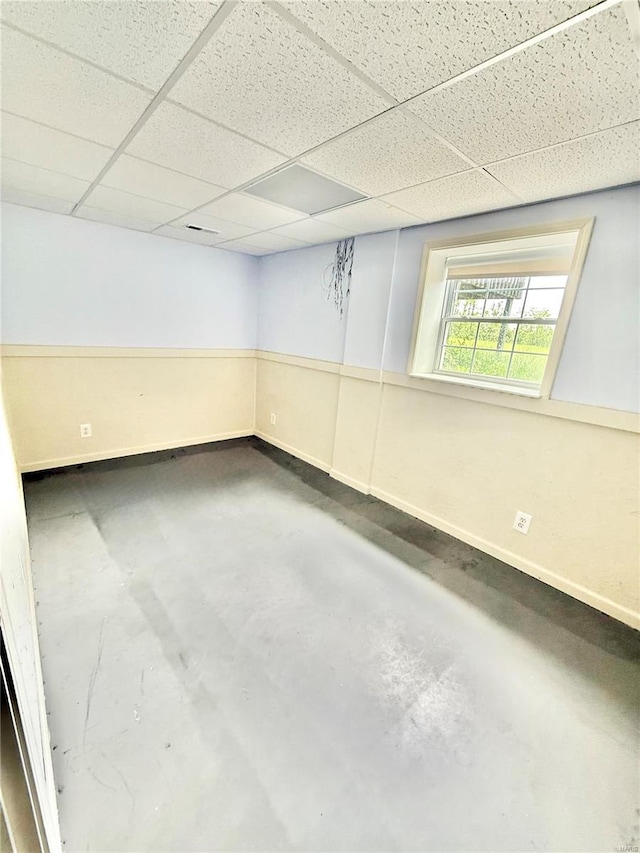 interior space featuring baseboards, concrete floors, and a paneled ceiling