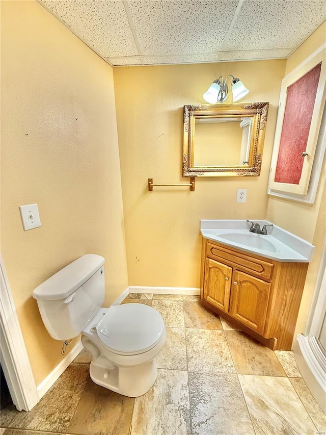 bathroom featuring vanity, baseboards, toilet, and a paneled ceiling