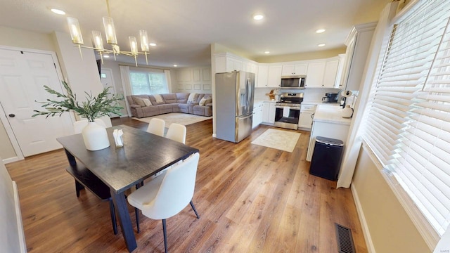 dining space with recessed lighting, a notable chandelier, light wood finished floors, and visible vents