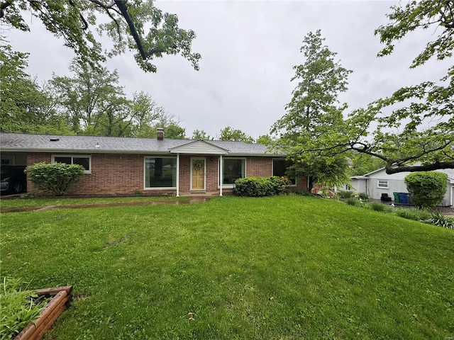 view of front of home featuring a chimney, a front yard, and brick siding
