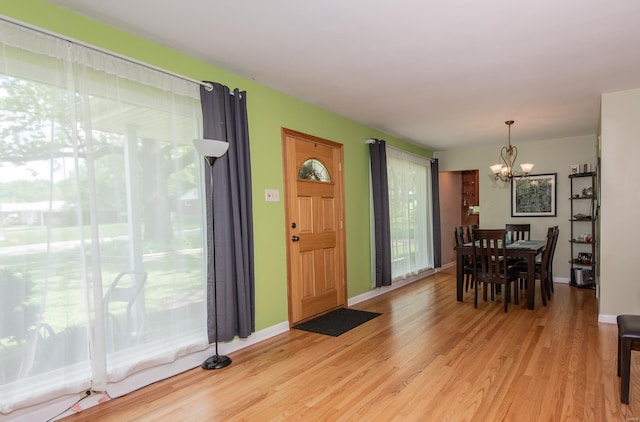 entrance foyer featuring a chandelier, baseboards, and light wood-style floors