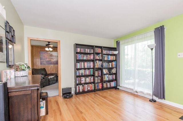 living area featuring baseboards, a ceiling fan, and wood finished floors