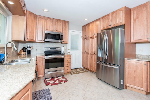 kitchen with a sink, light stone counters, recessed lighting, backsplash, and appliances with stainless steel finishes