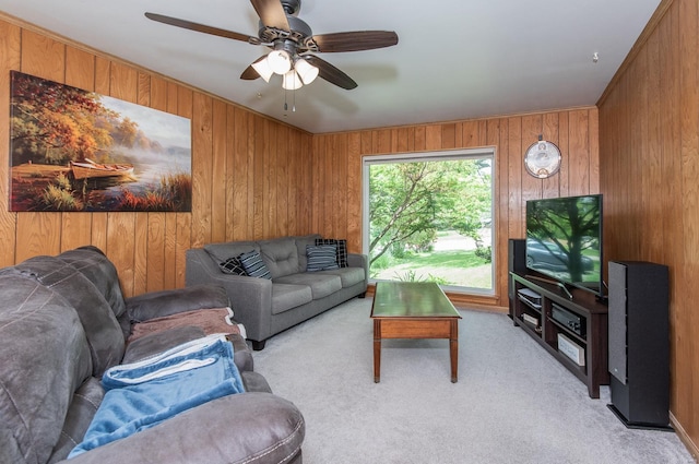 living area featuring light carpet, wood walls, and a ceiling fan