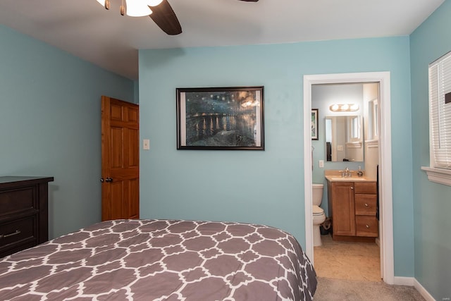 bedroom with ensuite bathroom, light carpet, ceiling fan, and a sink