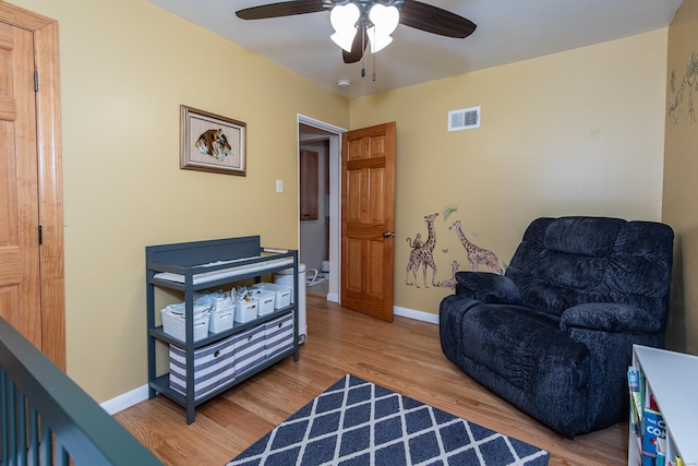 living area featuring baseboards, ceiling fan, visible vents, and wood finished floors