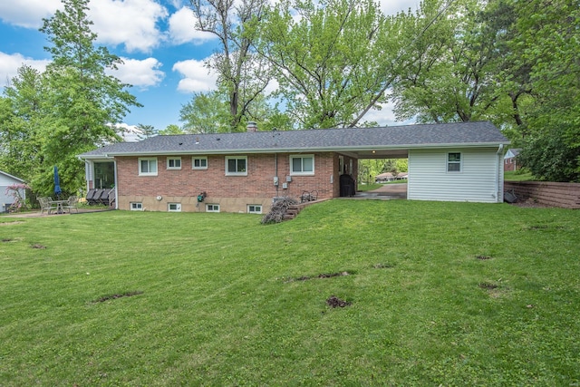 back of property featuring brick siding, a yard, a chimney, and an attached carport
