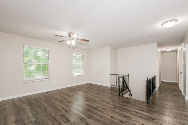 spare room featuring baseboards, a ceiling fan, and dark wood finished floors