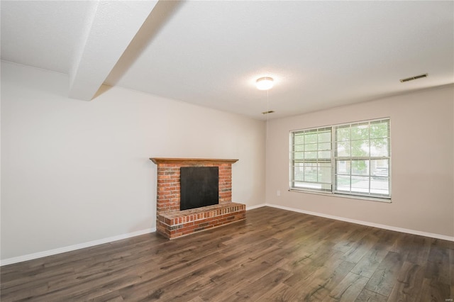 unfurnished living room featuring visible vents, baseboards, dark wood-style floors, and a fireplace