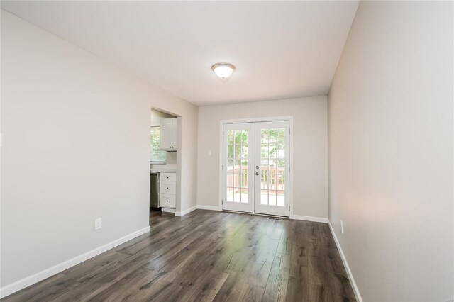 empty room featuring baseboards, dark wood finished floors, and french doors
