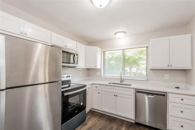 kitchen featuring white cabinets, appliances with stainless steel finishes, a sink, light countertops, and dark wood-style floors