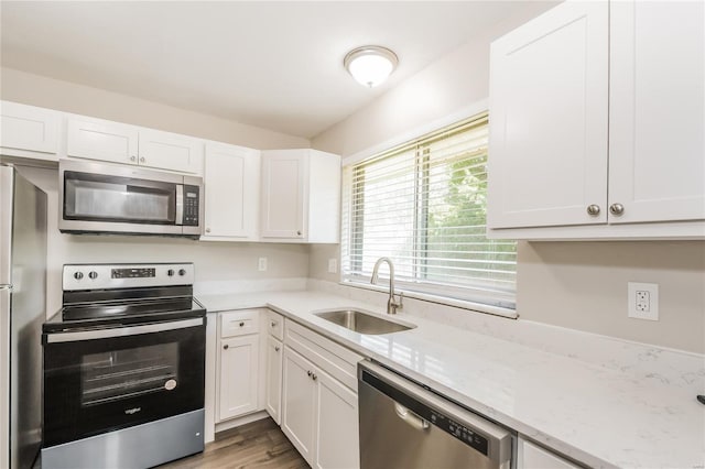 kitchen featuring white cabinetry, light stone countertops, appliances with stainless steel finishes, and a sink