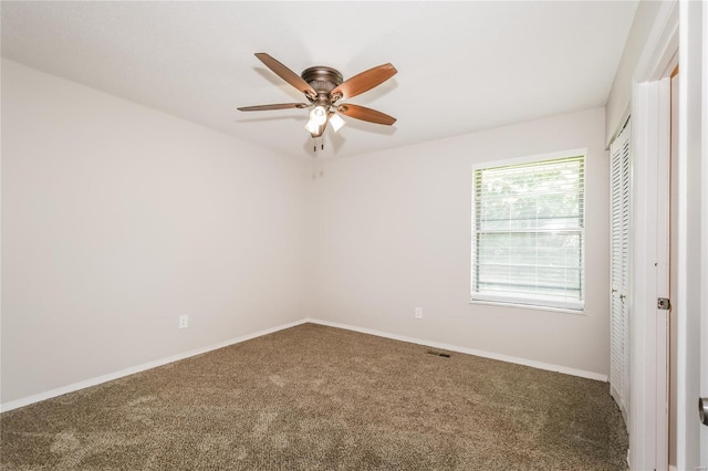 empty room with baseboards, carpet flooring, a ceiling fan, and visible vents