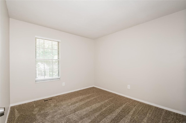 unfurnished room with dark carpet, baseboards, and visible vents