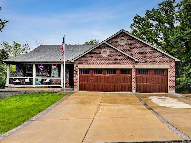 ranch-style home with a porch, brick siding, driveway, and a garage