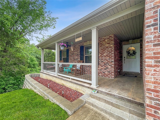 doorway to property featuring covered porch and brick siding