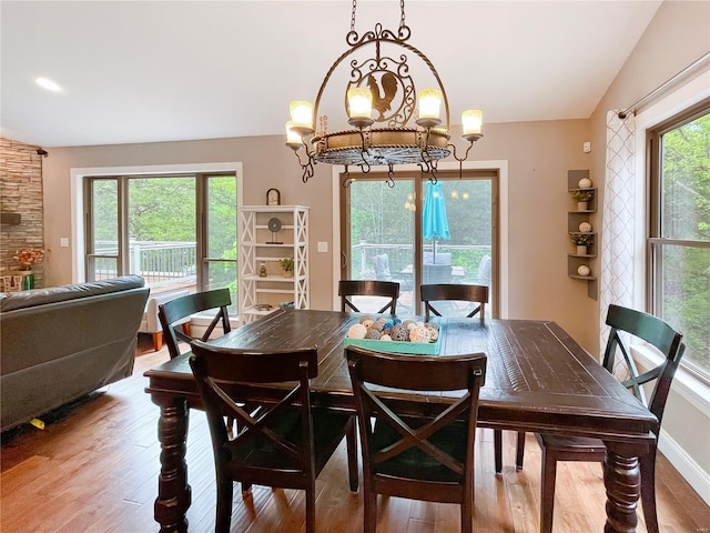dining space with wood finished floors, a notable chandelier, and vaulted ceiling