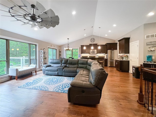 living area with high vaulted ceiling, visible vents, wood finished floors, and ceiling fan with notable chandelier
