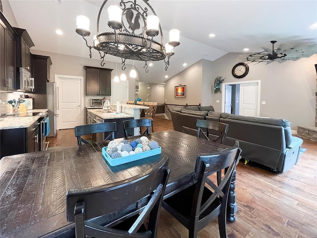 dining room featuring recessed lighting, ceiling fan with notable chandelier, wood finished floors, and vaulted ceiling