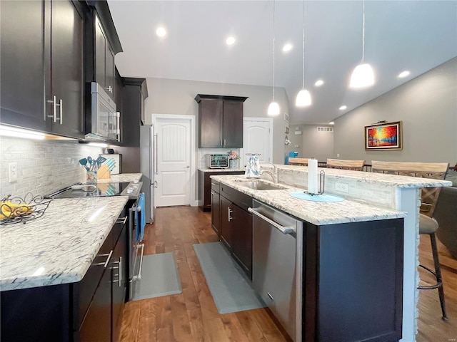kitchen with a breakfast bar area, dark wood-style floors, a sink, vaulted ceiling, and stainless steel appliances