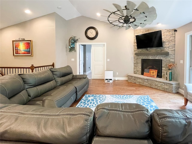 living area featuring ceiling fan, a stone fireplace, wood finished floors, and lofted ceiling