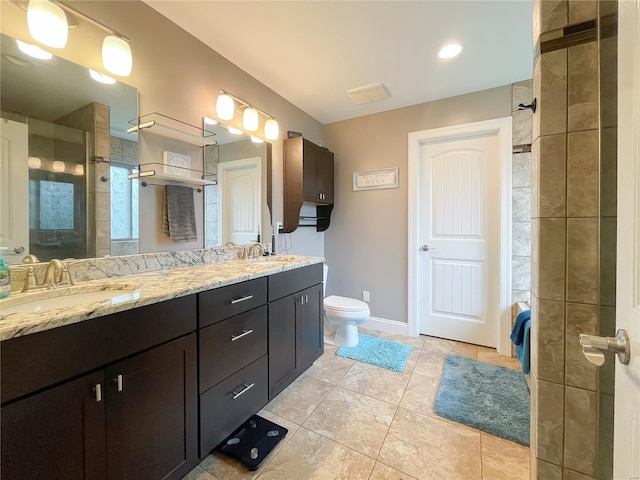 bathroom with double vanity, toilet, tile patterned floors, a sink, and a tile shower