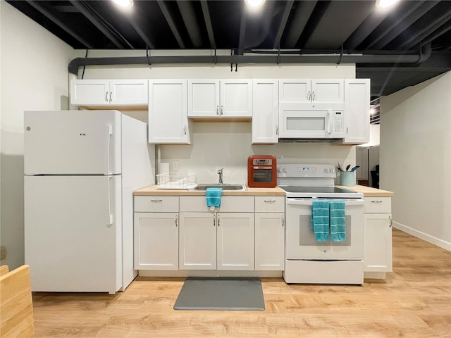 kitchen with white appliances, light wood-style floors, light countertops, white cabinets, and a sink