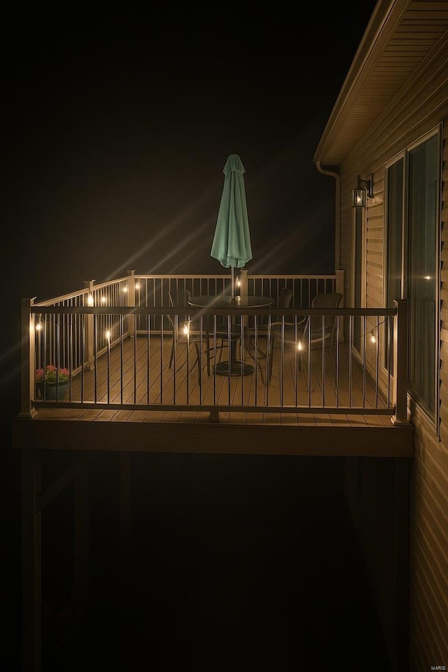 deck at night featuring outdoor dining space