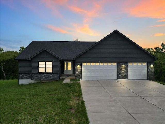 view of front of home featuring a garage, a lawn, concrete driveway, and stone siding