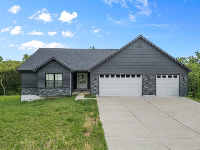 view of front of property featuring stone siding, an attached garage, driveway, and a front yard