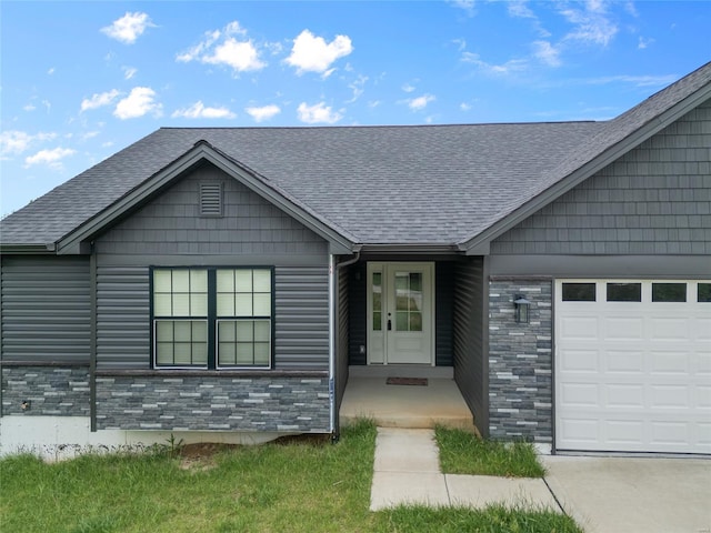 doorway to property with a garage, roof with shingles, and stone siding