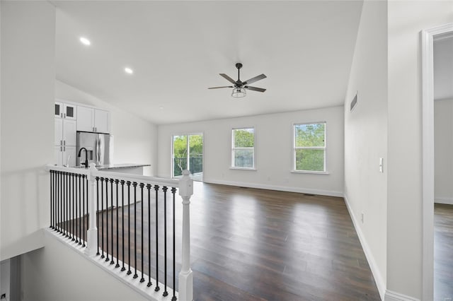unfurnished living room featuring plenty of natural light, a ceiling fan, dark wood finished floors, and visible vents