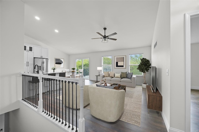living area featuring visible vents, a ceiling fan, dark wood-type flooring, and a healthy amount of sunlight