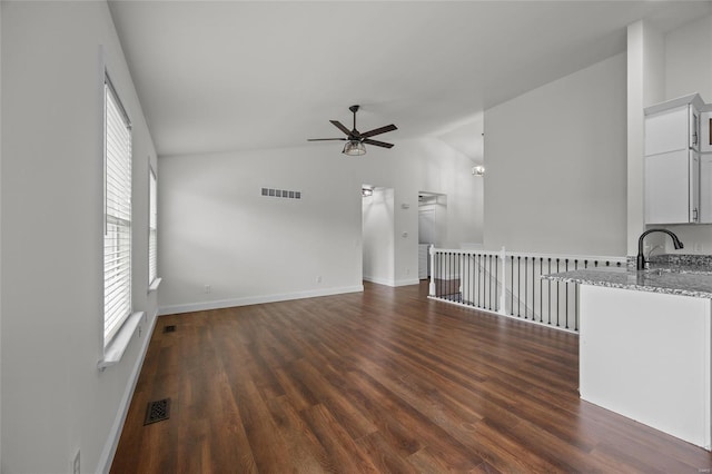 unfurnished living room featuring dark wood-style flooring, a ceiling fan, visible vents, and lofted ceiling