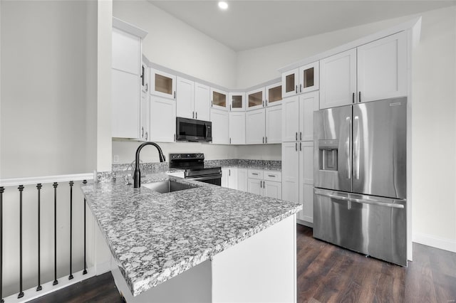kitchen featuring a sink, light stone counters, white cabinets, a peninsula, and stainless steel appliances