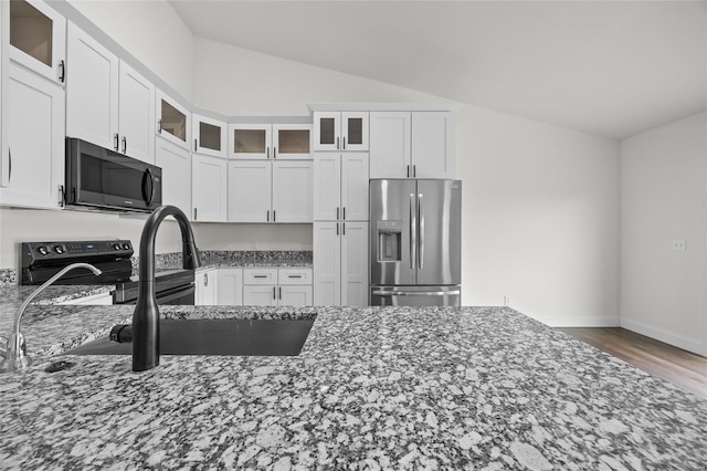kitchen with white cabinets, electric range oven, stone counters, lofted ceiling, and stainless steel refrigerator with ice dispenser