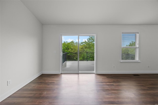 spare room with baseboards and dark wood-style floors