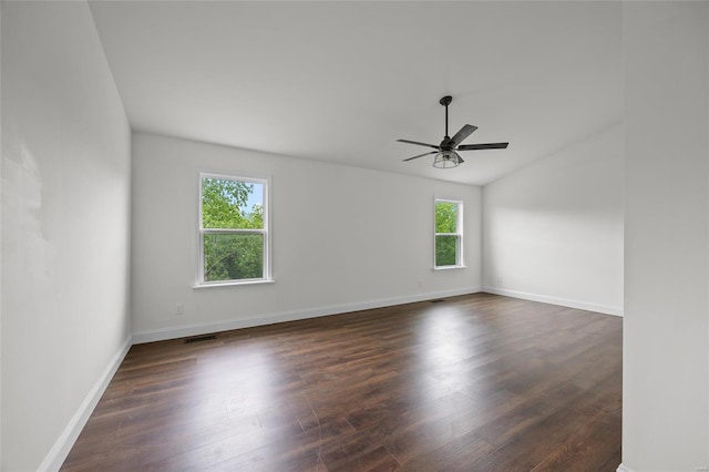 empty room featuring a ceiling fan, visible vents, vaulted ceiling, baseboards, and dark wood-type flooring