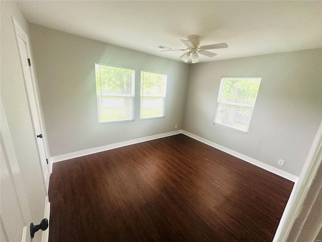 unfurnished room featuring visible vents, a ceiling fan, baseboards, and dark wood-type flooring