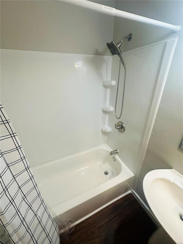 bathroom featuring shower / bathtub combination with curtain, a sink, and wood finished floors
