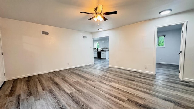 spare room with visible vents, a ceiling fan, baseboards, and wood finished floors