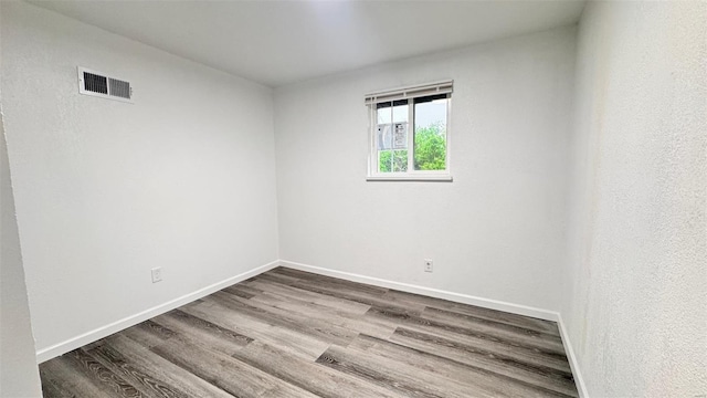 empty room featuring baseboards, dark wood-style floors, and visible vents