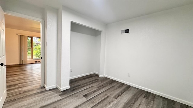 empty room featuring baseboards, visible vents, and wood finished floors