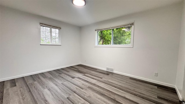 unfurnished room featuring a wealth of natural light, wood finished floors, and visible vents