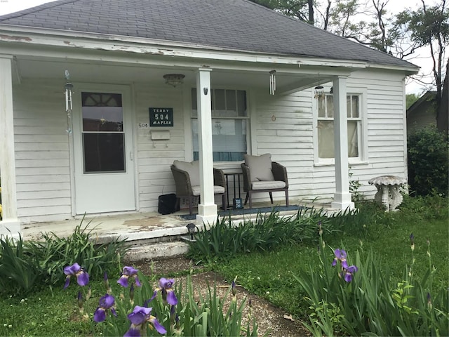 exterior space with a porch and a shingled roof