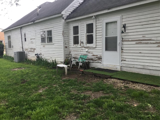 back of property featuring a yard, central AC, and roof with shingles